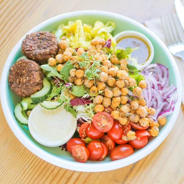 A vibrant Kitchen Mouse salad with falafel, roasted chickpeas, tomatoes, cucumbers, and red onion.