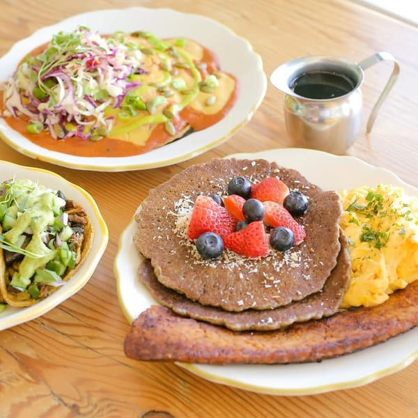 Kitchen Mouse breakfast spread with pancakes, scrambled eggs, bacon, tacos, and a chilaquiles-like dish.