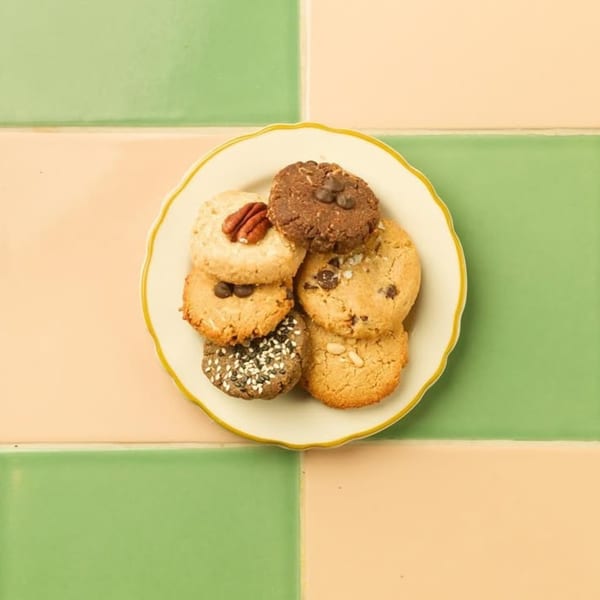 Assortment of Kitchen Mouse cookies on a white plate with a green and peach tiled background.